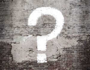 white question mark painted on a grey brick wall