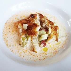 white bowl with cod chorizo and leeks in a cream sauce
