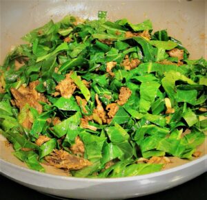 a close up of a wok full of Chinese 5 spiced meat with vegetables and spring greens