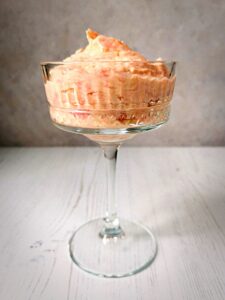 A tall stemmed glass filled with rhubarb fool on a grey background